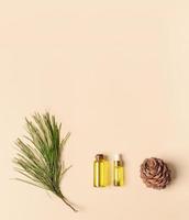 huile essentielle de cèdre aromatique spa conifère dans de petites bouteilles en verre, branche, cône sur fond beige avec espace de copie. photo