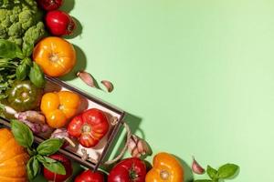 vue de dessus récolte de légumes de la ferme dans une petite boîte en bois et sur fond vert pastel. voir ci-dessus. copier l'espace pour le texte. photo