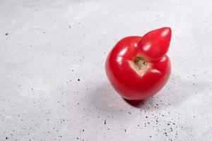 gros plan une tomate rouge mûre laide sur fond de béton gris.