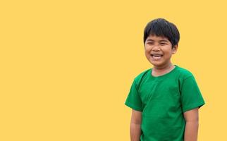 le garçon portait une chemise verte et se tenait souriant. sur fond jaune photo