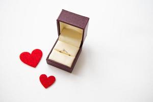 beaux coeurs rouges sur fond blanc avec un anneau dans une boîte. demandes en mariage. photo