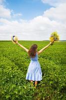 la jeune fille est debout dans le champ avec un bouquet de fleurs jaunes et un chapeau de paille photo