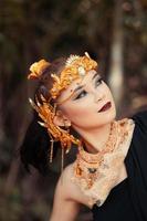 visage en gros plan d'une femme asiatique maquillée portant une couronne en or et des accessoires en or avec de beaux visages photo