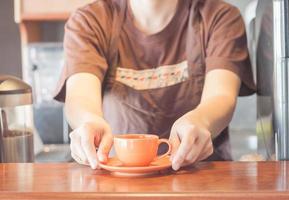 barista offrant une tasse de café orange photo