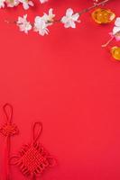 concept de design du nouvel an lunaire chinois - beau noeud chinois avec fleur de prunier isolé sur fond rouge, mise à plat, vue de dessus, mise en page aérienne. photo