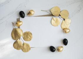 maquette, oeufs de pâques dorés et noirs avec des feuilles d'eucalyptus dorées. photo