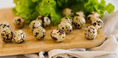 Oeufs de caille de ferme sur une planche de cuisine en bois avec des feuilles de laitue verte.le concept d'une alimentation saine appropriée. photo