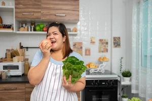 les enceintes asiatiques apprennent à cuisiner des repas sains à partir d'internet dans la cuisine, les grosses femmes préparent une salade de légumes pour les aliments diététiques et perdent du poids. concept d'alimentation saine photo