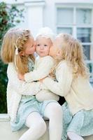 3 petites filles aux cheveux clairs se font un câlin. l'amour des soeurs. les filles de la météo s'aiment beaucoup. lien infirmier. relations chaleureuses dans la famille. photo douce par trois petites filles.