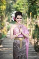 belle fille thaïlandaise en costume traditionnel thaïlandais dans le geste de salutation thaïlandais photo