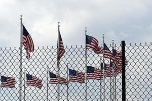 agitant des drapeaux américains derrière la grille de clôture photo