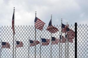 agitant des drapeaux américains derrière la grille de clôture photo