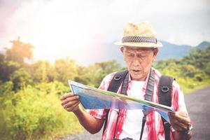 homme âgé randonnée randonnée ouvrir une carte papier pour étudier la route touristique naturelle. le concept de vie heureuse après la retraite. avec espace de copie. photo