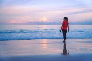 fille en cours d'exécution d'entraînement jogging sur la plage le matin. détendez-vous et heureux de courir sur la mer. en été photo