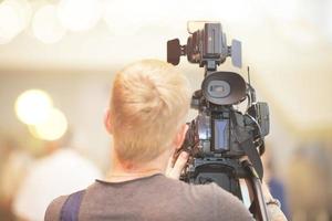 un vidéaste avec une caméra se tient debout avec son dos. photo