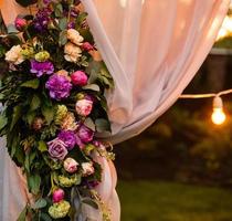 décoration de cérémonie de mariage au crépuscule faite de lanternes et de lampes dorées accrochées à un arbre et debout sur l'herbe avec des bougies allumées avec le tapis au milieu photo