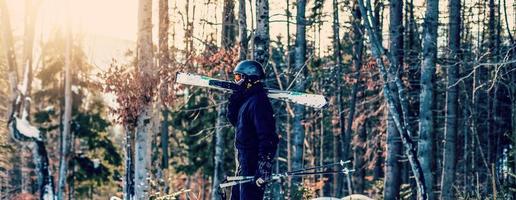 skieur tenant le ski et regardant de belles montagnes enneigées. jeune homme pensant et regardant la montagne enneigée avec espace de copie. vue latérale du gars du skieur d'hiver avec masque tenant l'équipement de ski en plein air. photo