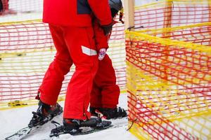 petite fille en rouge apprenant à skier avec l'aide d'un adulte photo