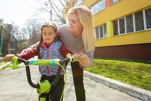 mère enseignant sa fille à vélo dans le parc, activité amusante en plein air en famille. photo