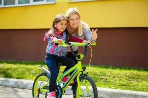 portrait d'une femme souriante avec sa fille à bicyclette photo