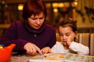 mère et fille dans un café lisent un livre photo