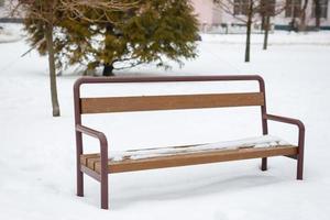 magasin de fer, noir avec un siège en bois, se dresse dans un parc d'hiver, dans la neige photo