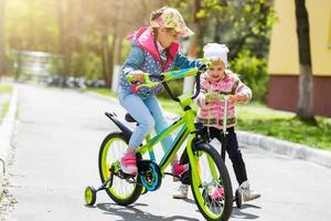 deux enfants en scooter et vélo dans le parc, sport familial photo