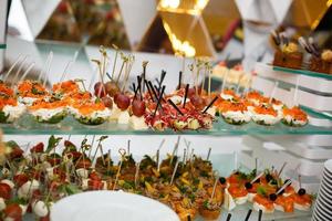 table de banquet de restauration joliment décorée avec des salades de profiteroles de hamburgers et des collations froides photo