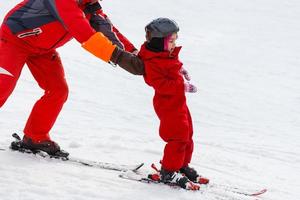 un moniteur de ski professionnel enseigne à un enfant à skier par une journée ensoleillée sur une station de montagne avec soleil et neige. famille et enfants vacances actives. photo