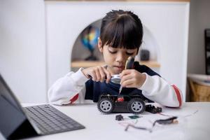les étudiants asiatiques apprennent à la maison à coder des voitures robotisées et des câbles de cartes électroniques dans la tige, la vapeur, la technologie des sciences de l'ingénierie mathématique le code informatique dans la robotique pour le concept des enfants photo