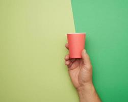 main masculine tenant une tasse jetable en papier rouge sur fond vert photo