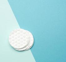 disques ronds en coton blanc pour procédures cosmétiques sur fond bleu photo
