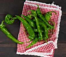 gousses de piment vert dans un panier en osier rond sur une table en bois marron photo