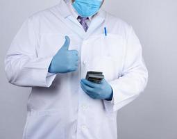 médecin en blouse blanche, portant des gants stériles bleus, le médecin tient un paquet de papier-monnaie photo