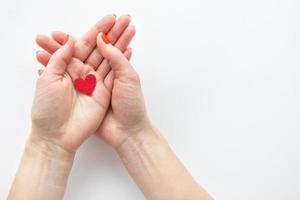 les mains féminines tiennent un petit coeur rouge. le concept de soin et d'amour. photo