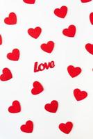 le fond qui se compose de coeurs rouges, l'inscription love au milieu des coeurs. photographie verticale. concept d'amour, carte de voeux pour la saint-valentin. photo