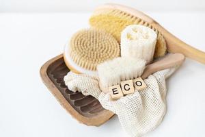 zéro déchet, salle de bain et mode de vie durables. brosse en bambou, éponge de luffa, brosse de massage de cactus sur fond blanc. l'inscription eko en lettres de bois. photo