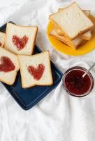 pain grillé sur lequel le cœur est fait de confiture. concept de petit-déjeuner surprise au lit. romance pour st. La Saint-Valentin. photo