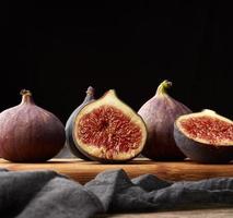 figues violettes mûres entières et coupées en deux sur une serviette noire, discret photo