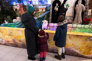 mère avec enfants visitent la crèche de noël à l'église. photo