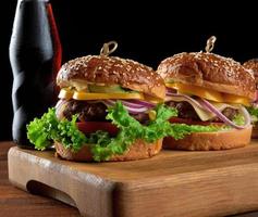 délicieux burgers avec escalope de bœuf frite, tomate, laitue et oignons, pain croustillant à la farine de blé blanc aux graines de sésame photo