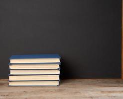 pile de divers livres cartonnés sur le fond d'un tableau de craie noire vide photo