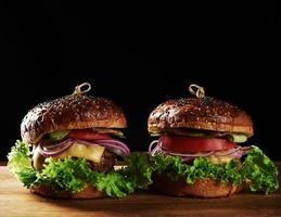 délicieux burgers avec escalope de bœuf frite, tomate, laitue et oignons, pain croustillant à la farine de blé blanc aux graines de sésame photo