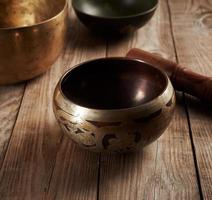 bol en cuivre chantant tibétain avec un battant en bois sur une table en bois marron photo