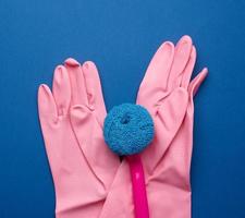 gants en caoutchouc rose pour le nettoyage, brosses sur fond bleu photo