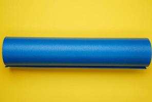 tapis en néoprène bleu torsadé pour le yoga et le sport sur fond jaune photo