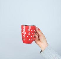 tasse en céramique rouge dans une main féminine sur fond blanc photo