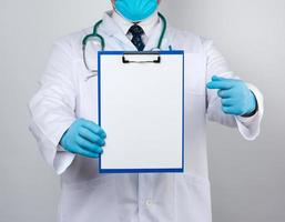médecin en blouse médicale blanche, gants en latex bleu tenant un porte-papier photo