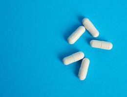 capsules blanches sur fond bleu, vue de dessus des pilules photo