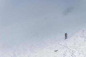 alpiniste solitaire pris dans le brouillard un jour d'hiver dans les montagnes atteignant le sommet. conditions exigeantes et difficiles pour la randonnée hivernale dans des conditions météorologiques difficiles. copier coller l'espace. photo